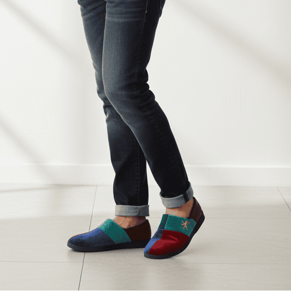 Men's slip-on slippers with multi-color panels, worn with jeans and sock cuffs