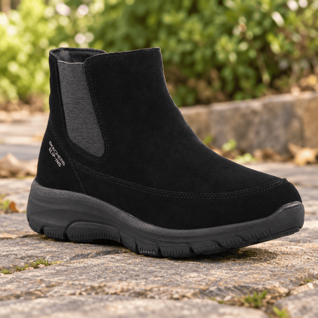 Women's black Chelsea slip-on boot with elastic gore panels on outdoor pavement