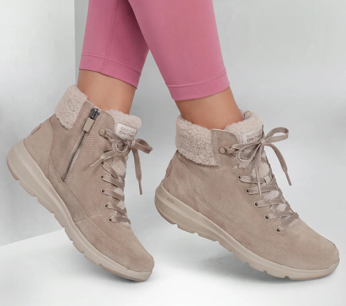 Taupe suede lace-up winter boots with faux-fur trim, worn with jeans