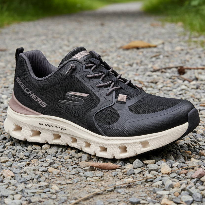 A Skechers Glide-Step athletic sneaker in black and dark gray with a beige sole, shown from a three-quarters angle on a white background.