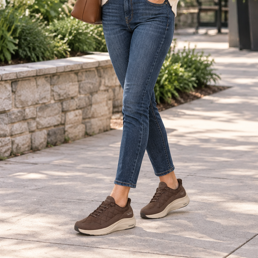 Women's brown lace-up sneaker with white foam midsole worn with blue jeans