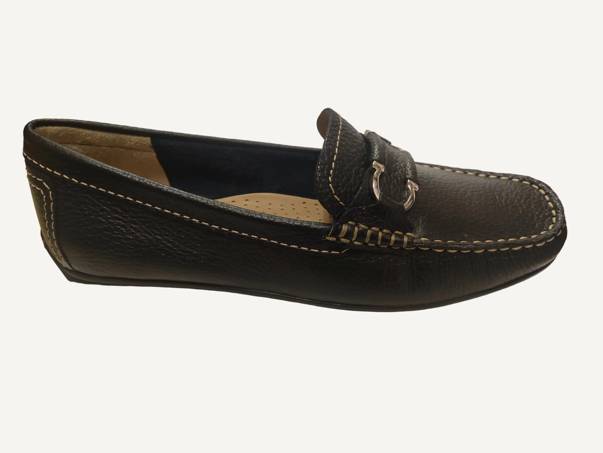 Black leather loafer shoe on a white surface with a blurred background