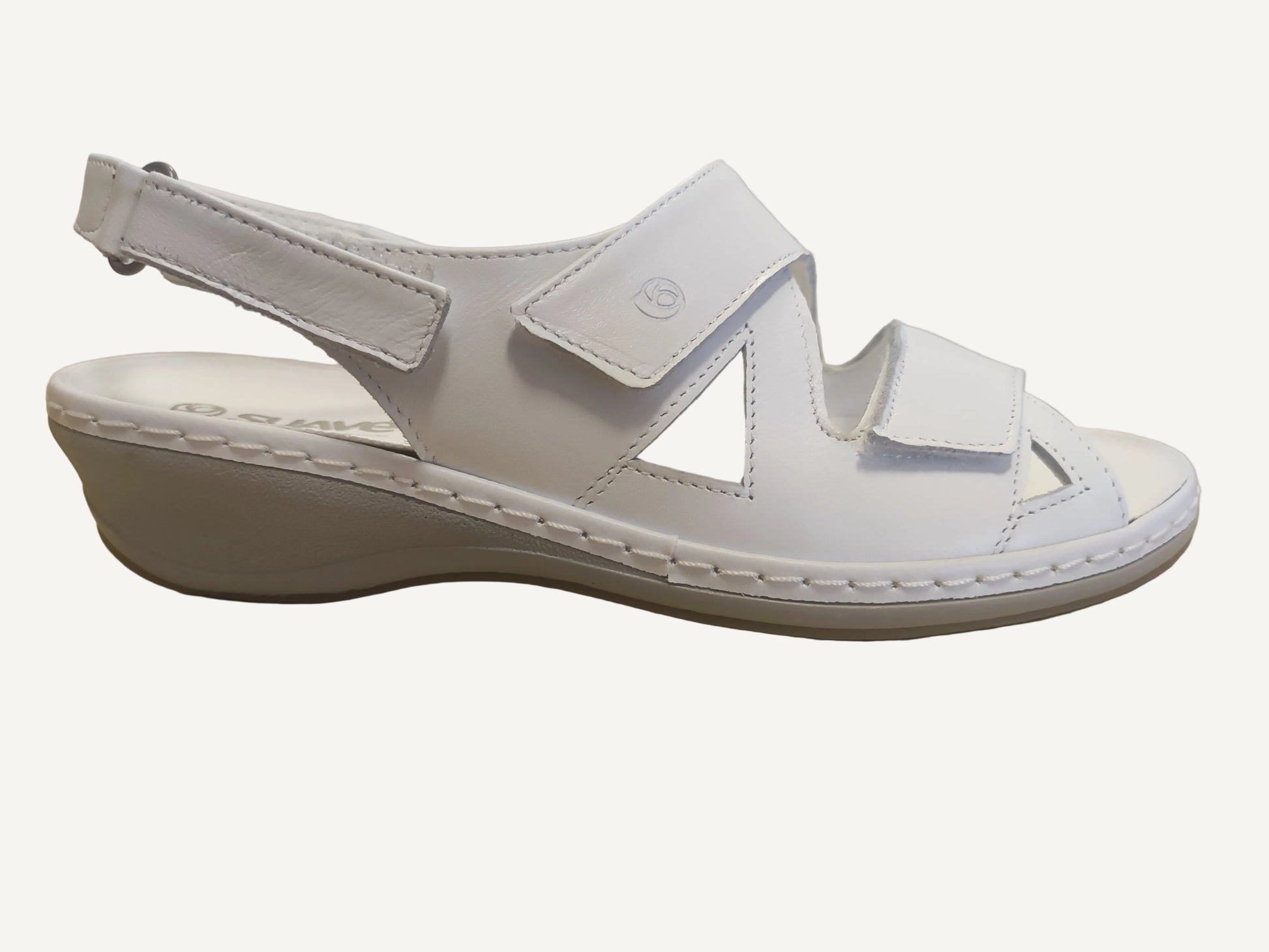 White sandal with strap on a wooden surface