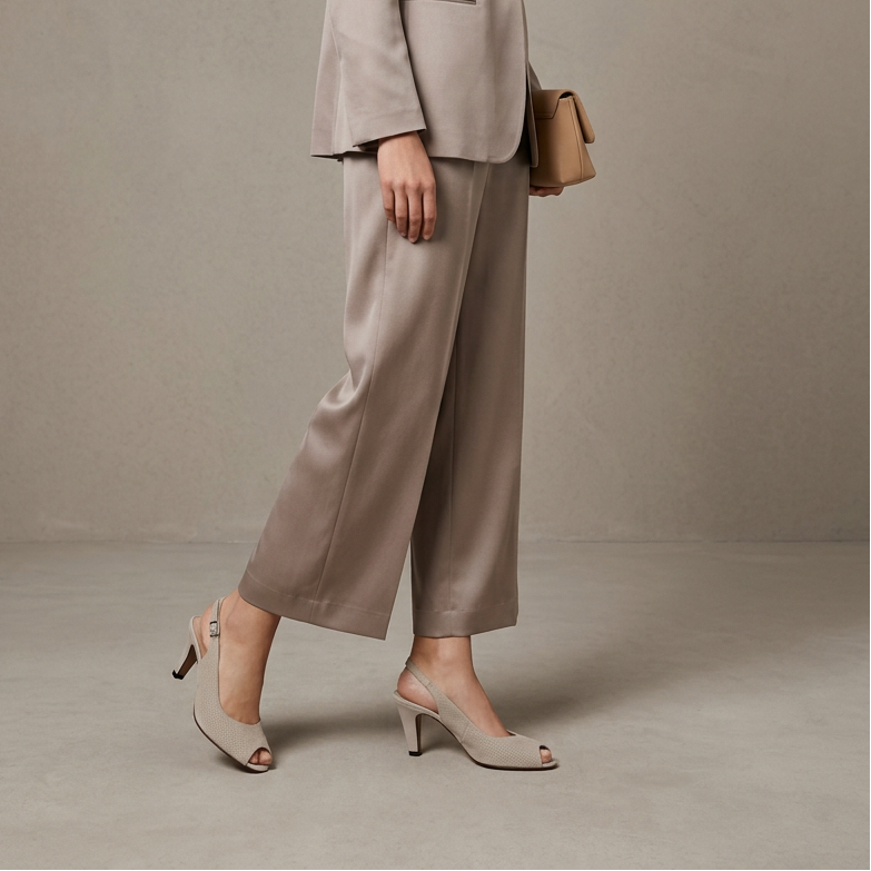 Women's light gray slingback sandals with mid block heels on taupe trousers