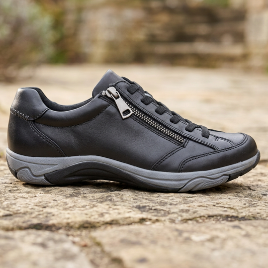 Black leather women's lace-up sneaker with side zip and rounded toe on outdoor ground