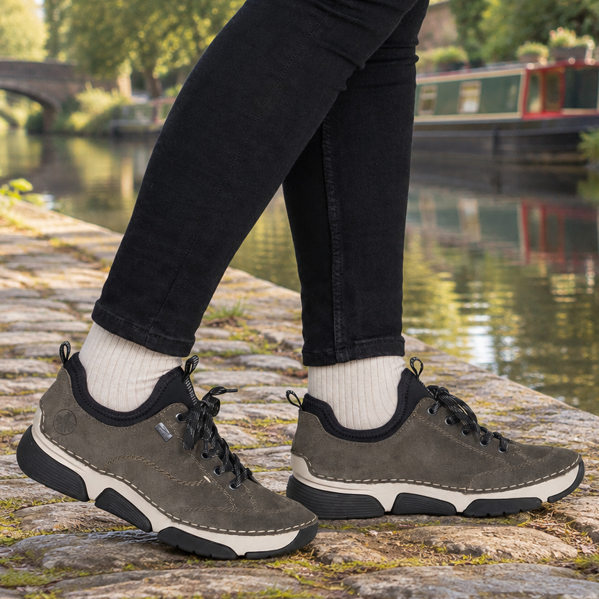 Women's grey suede slip-on sneakers with black laces and rubber sole on white socks