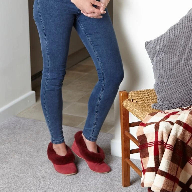 Women’s cherry red sheepskin slippers worn with jeans, featuring thick fuzzy uppers