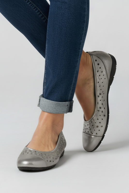 Silver flat shoes worn with blue jeans on a light gray background