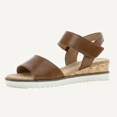 Brown sandal with cork wedge sole on a light beige background