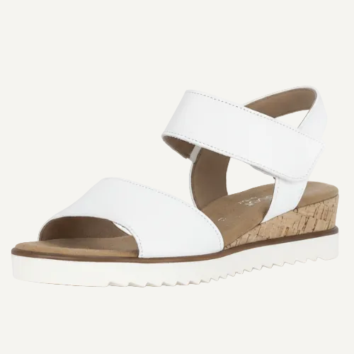 White sandal with a brown sole on a light beige background