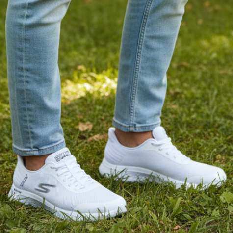 White sneakers worn with light blue jeans on a grassy background