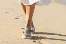 Woman in a white dress standing on a beach with palm trees in the background