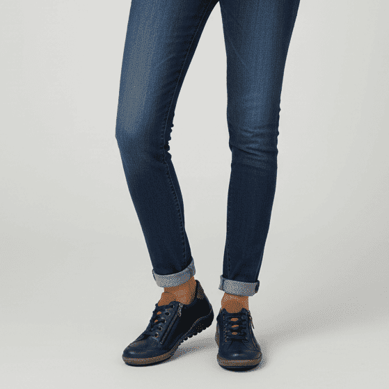 Navy zip sneakers with lace-up front and tan collar, worn with cuffed jeans